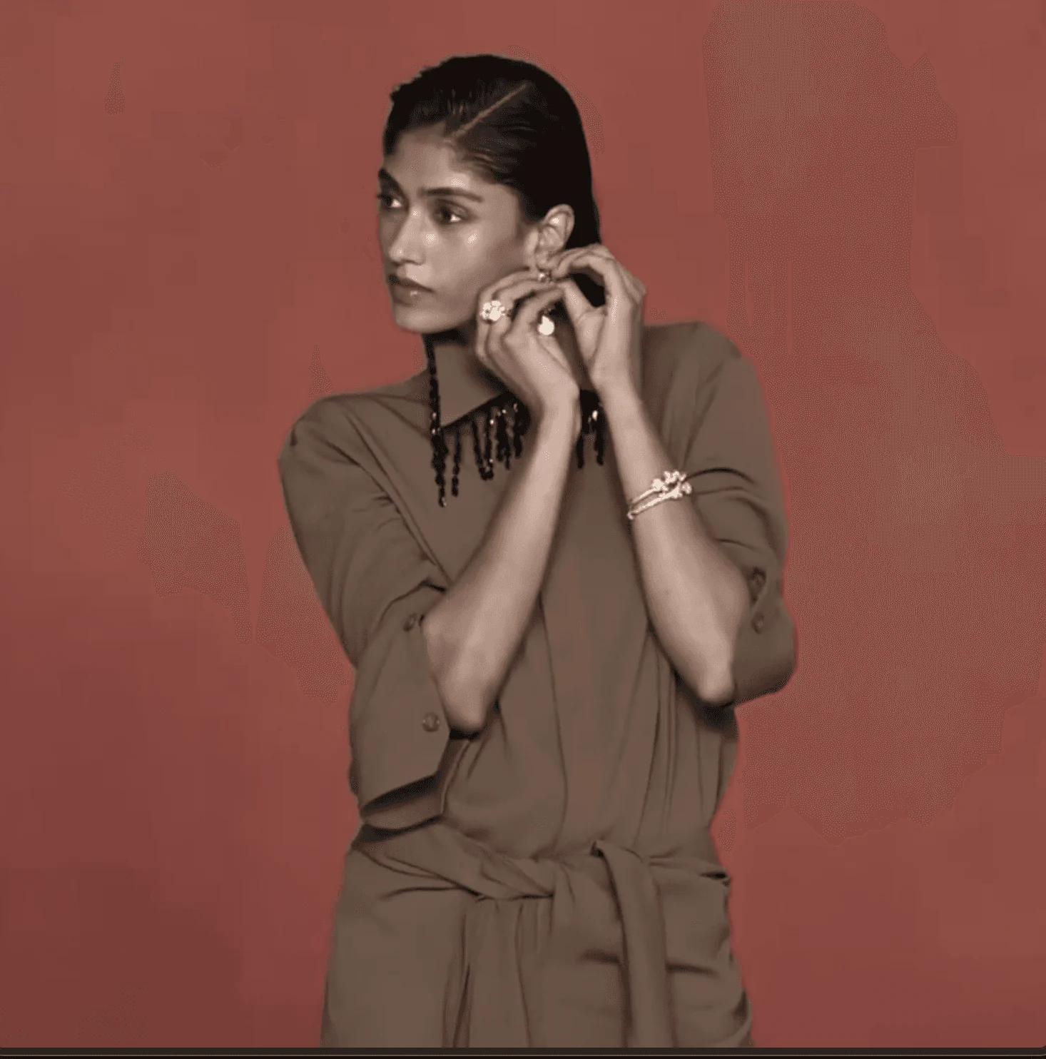 Model in sculptural silhouette against muted red backdrop, reflecting 431-88’s quiet strength